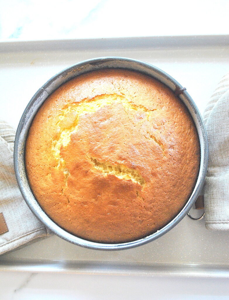A fully baked cake in a springform pan cooling.