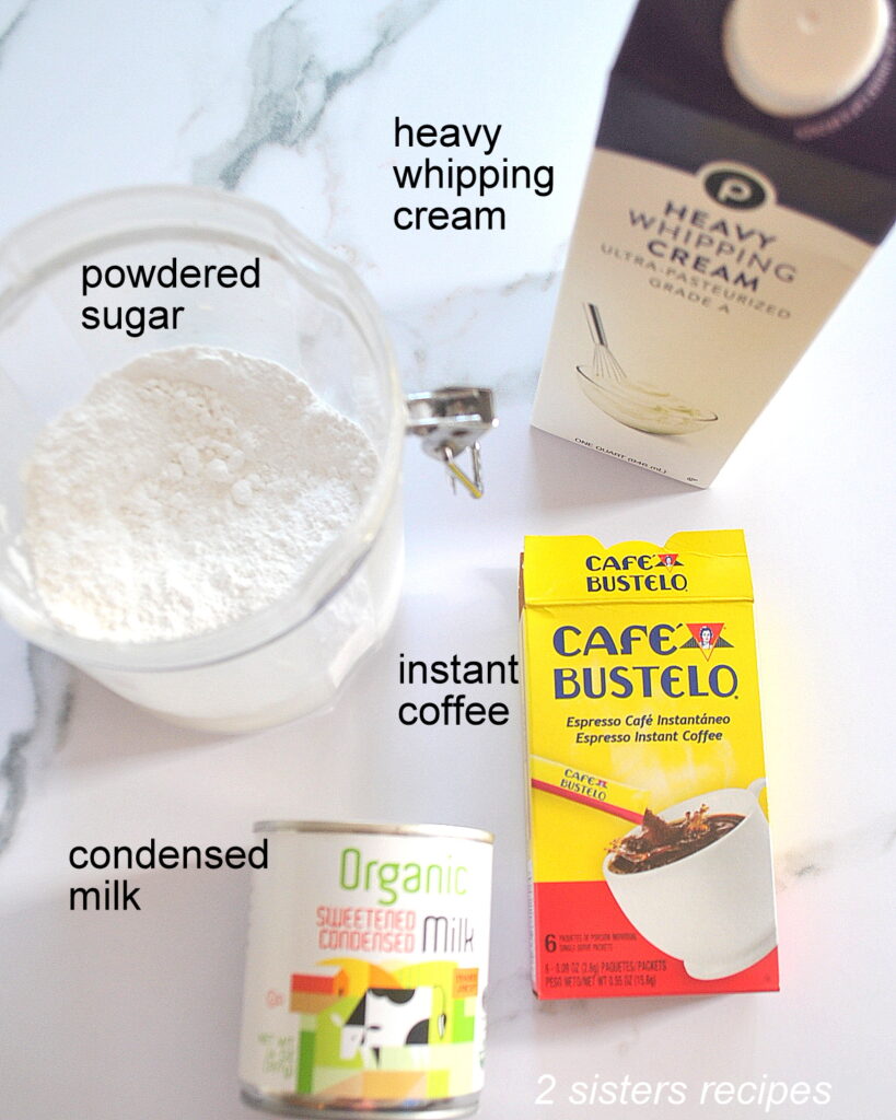 A carton of whipping cream, a canaster filled with powdered sugar, a box of instant coffee and can of condensed milk displayed on the table.