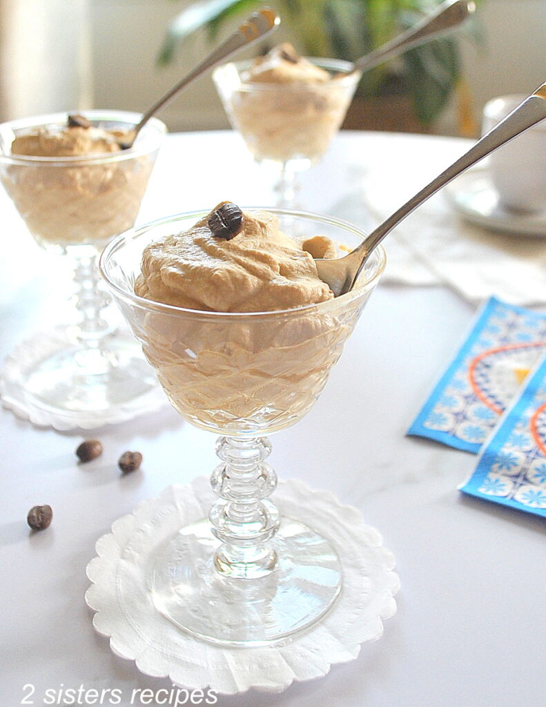 Three cordial glasses filled with a coffee cream and spoon.