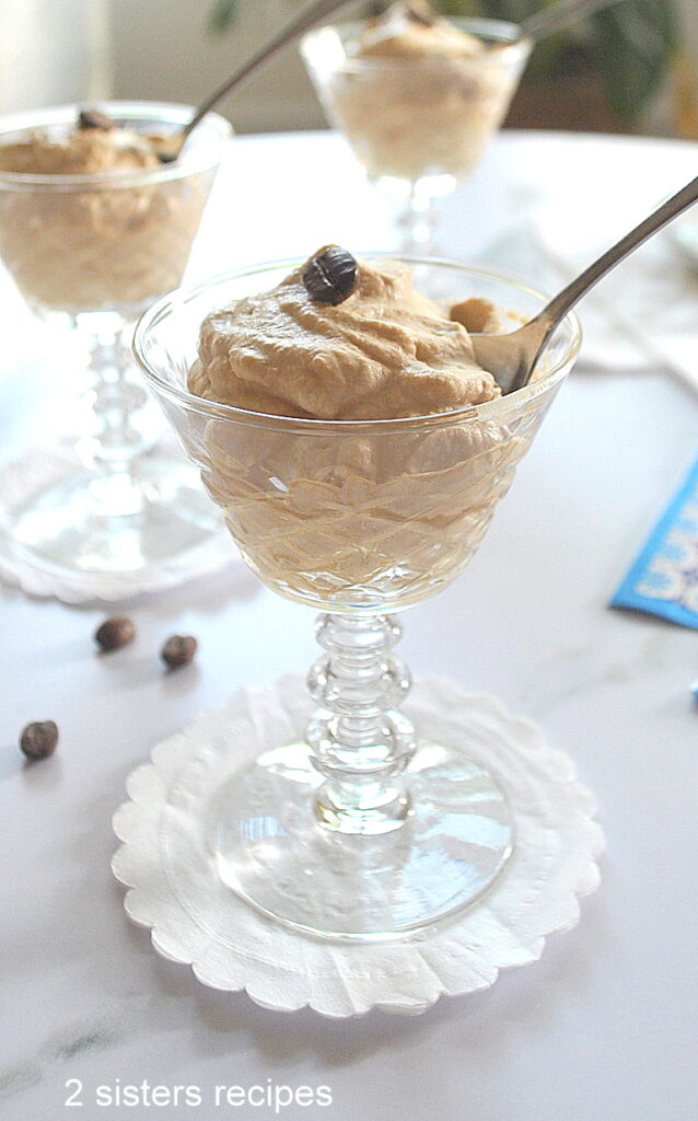 A cordial glass filled with coffee cream and a spoon.