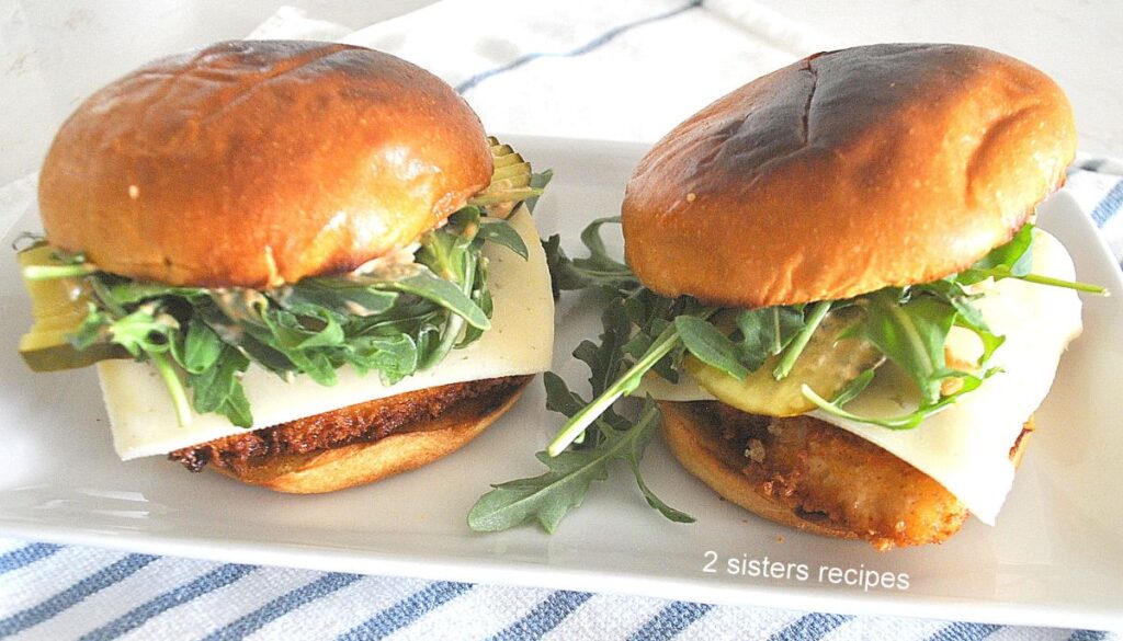 Two fish sandwiches set on a white platter.