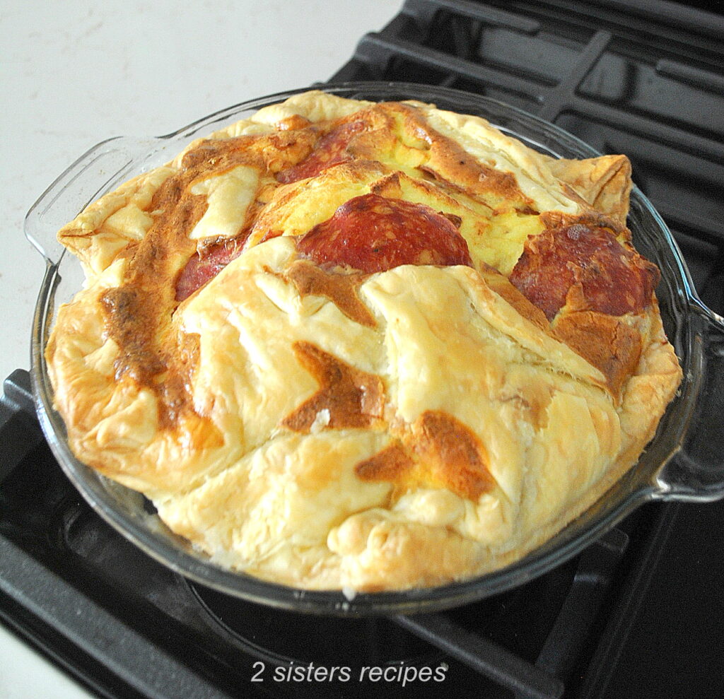 A fully baked quiche resting on stove top.