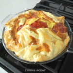 A fully baked quiche resting on stove top.