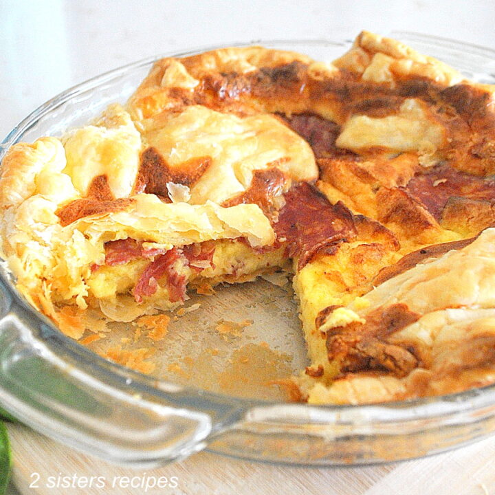 A slice of quiche taken from a glass pie dish.