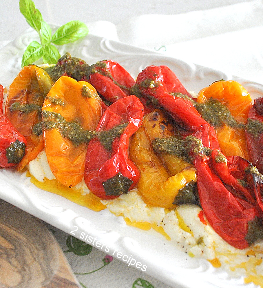 A white platter with a bed of ricotta with charred peppers.