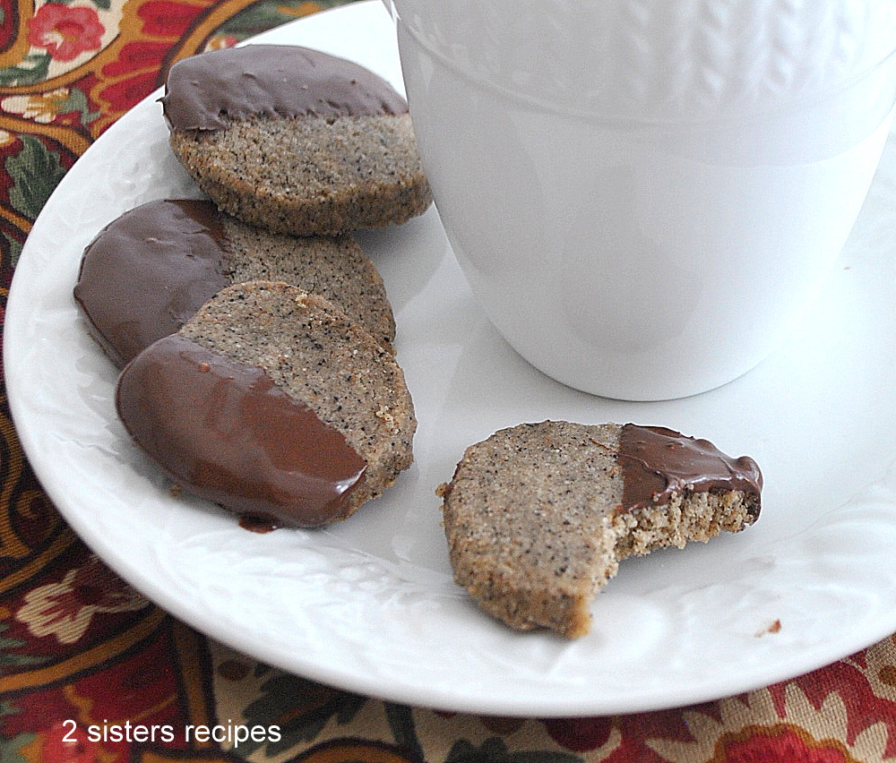 Four shortbread espresso flavored cookies placed on a white plate with a coffee mug.