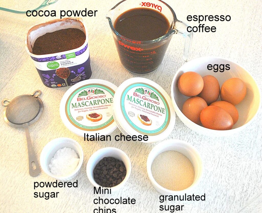 6 eggs in a bowl, 2 containers of Mascarpone, cup of espresso coffee, sugar, cocoa powder, and mini chocolate chips. 