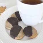 A white plate and coffee mug with 4 espresso shortbread cookies dipped in chocolate.