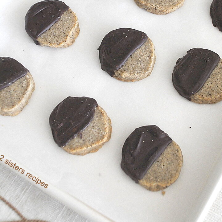 A baking sheet with baked espresso shortbread cookies dipped half way in chocolate.