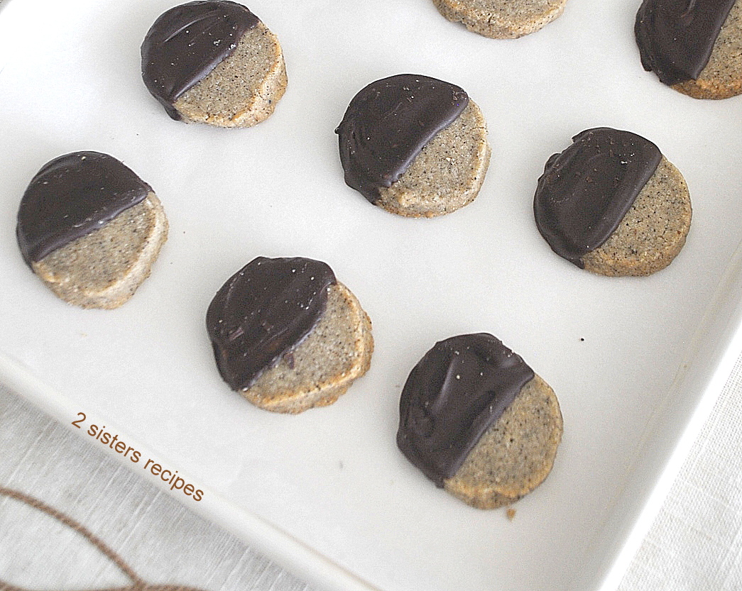 A baking sheet with baked espresso shortbread cookies dipped half way in chocolate.