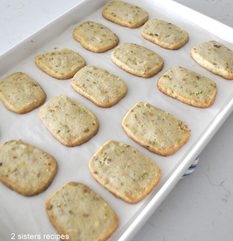 A baking sheet filled with baked pistachio shortbread cookies.