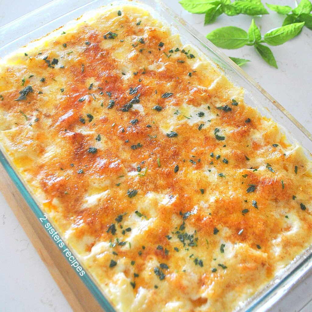 A pyrex glass baking dish filled with a baked potato and Gruyere cheese, casserole. topped with smoked paprika.