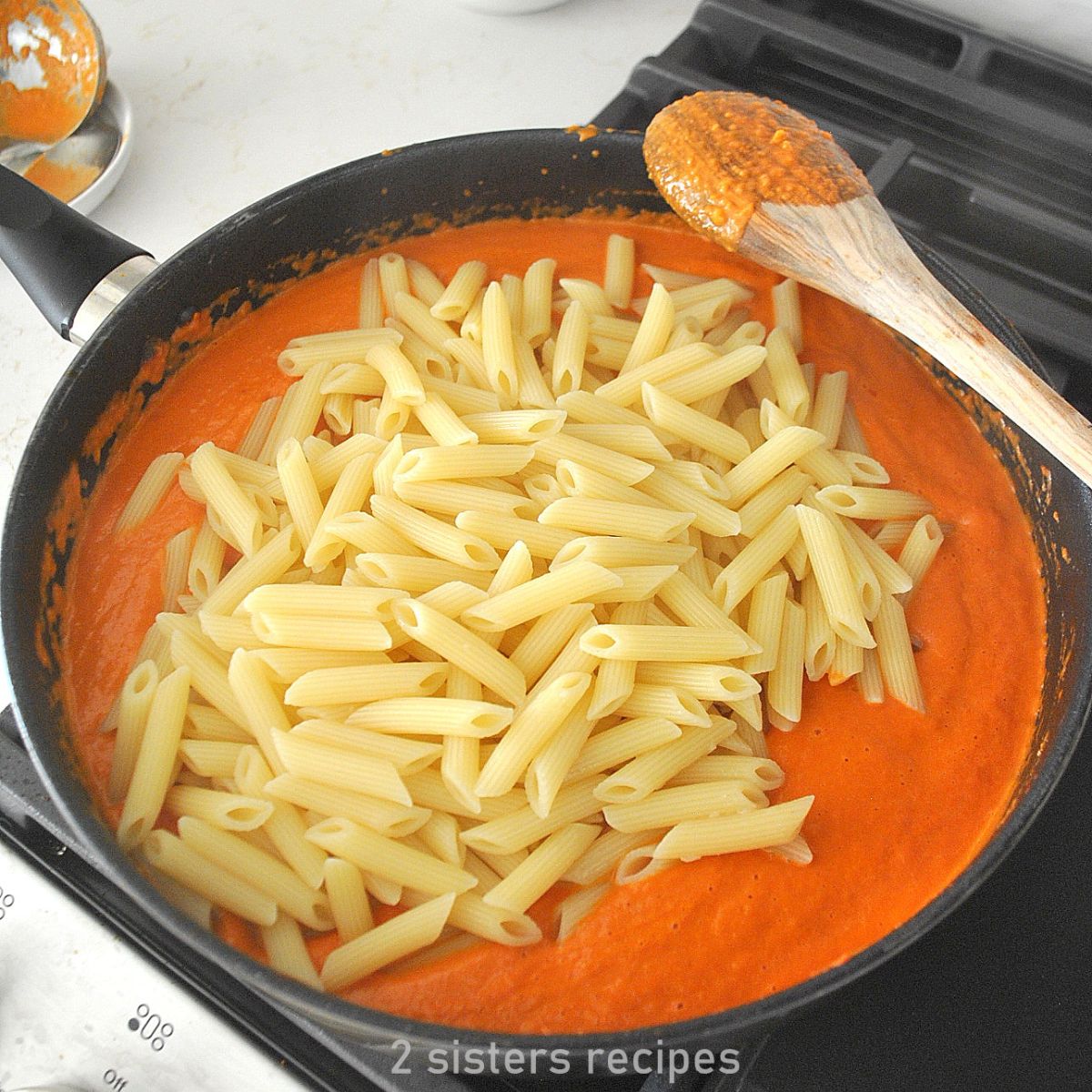A black skillet filled with Vodka sauce and penne pasta.