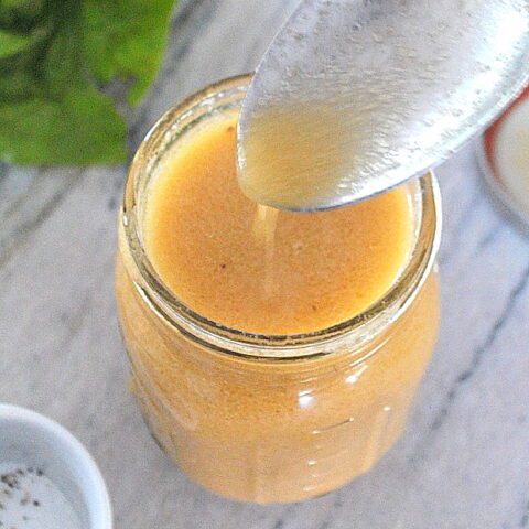 A spoonful of dressing from a mason jar.