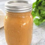A mason jar filled with a salad dressing.