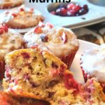A baked muffin split in half displayed to show the bits of cranberries inside.