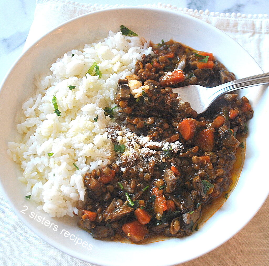 A forkful of mushroom and lentil stew with steamed rice on the side.
