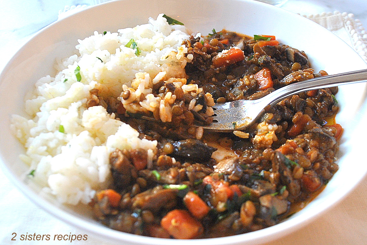 A forkful of a serving of mushroom and lentil stew with a side of white rice, served in a white plate.