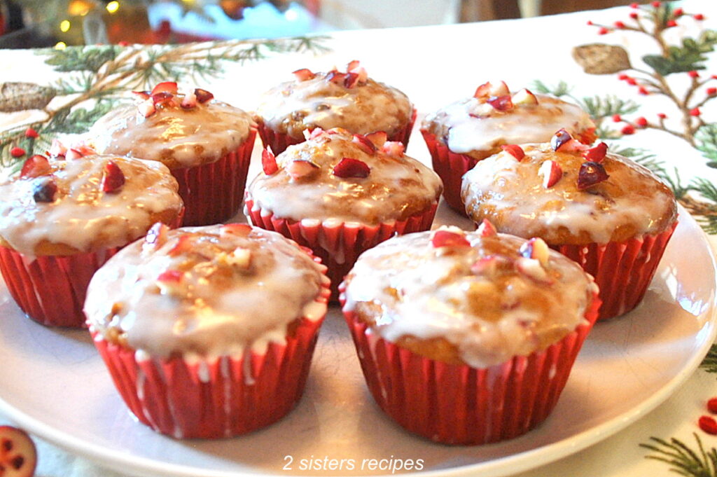 A white plate with eight baked muffins topped with glaze.