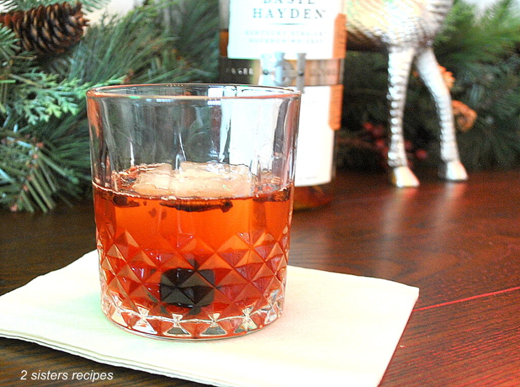 A whiskey glass filled with an Old Fashioned Cocktail and a cherry as garnish.