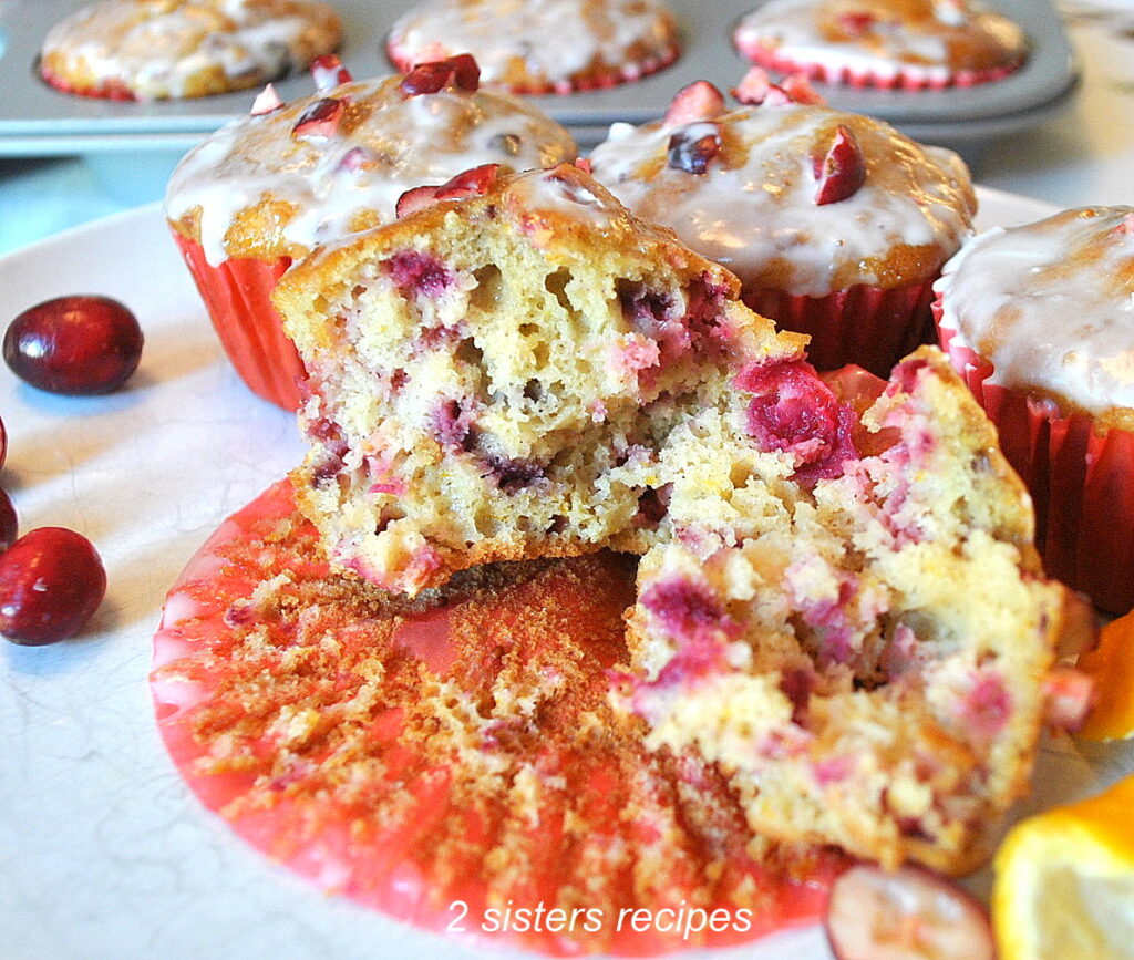 A muffin torn in half to show the bits of cranberries throughout the muffin.