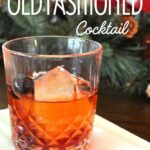 A cocktail glass filled with an Old Fashioned drink served on a napkin.