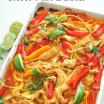 A sheet pan filled with strips of chicken, colorful peppers and slices of lime.