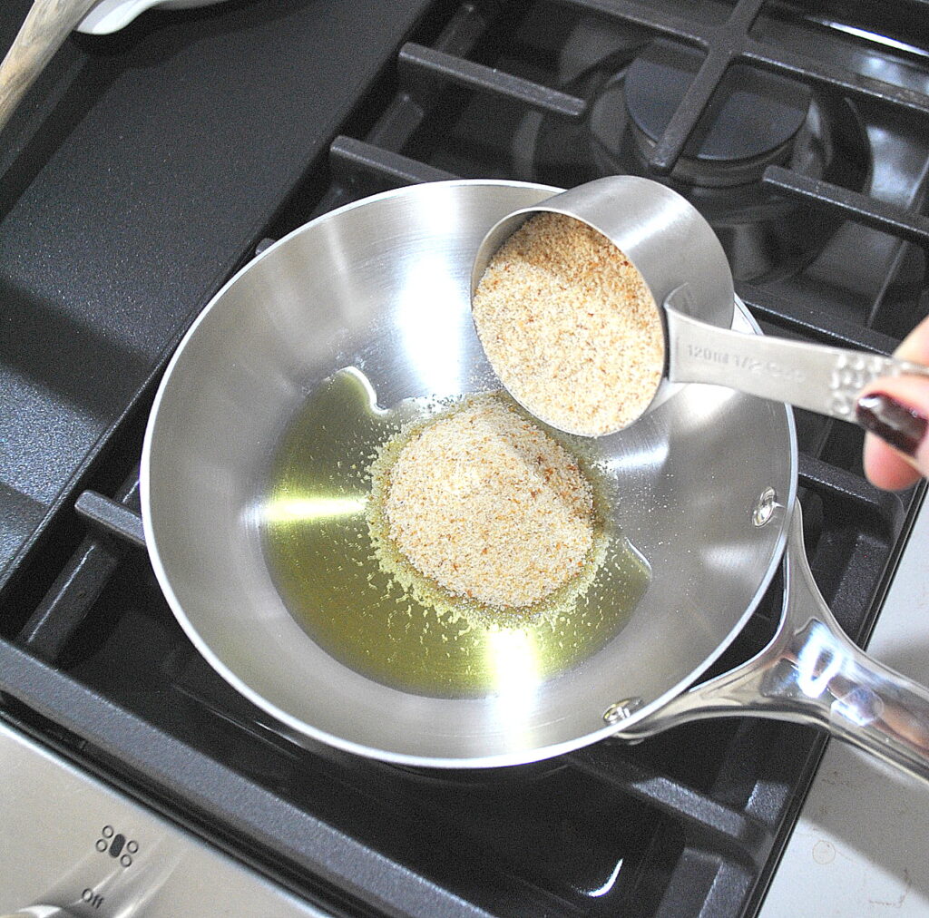 A small silver skillet with olive oil and bread crumbs added.