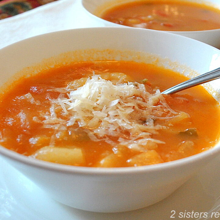 A bowl of soup with grated cheese on top and a spoon inside.