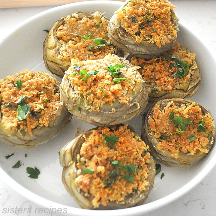 A white bowl filled with baked stuffed artichoke bottoms.