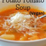 A bowl of potato and tomato soup with grated cheese on top.