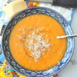 A blue bowl filled with creamy sweet potato soup with grated cheese on top.