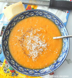 A blue bowl filled with creamy sweet potato soup with grated cheese on top.