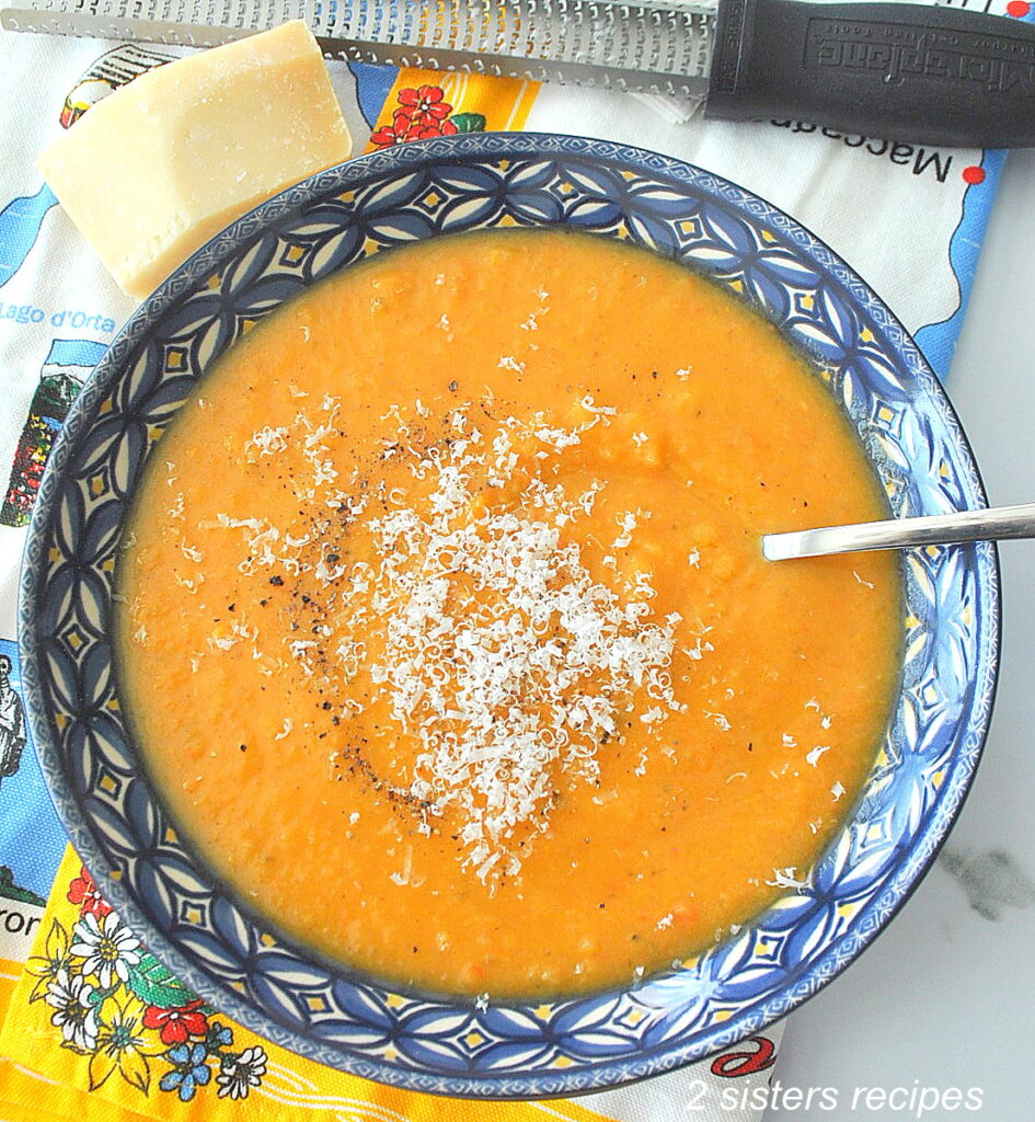 A blue bowl filled with creamy sweet potato soup with grated cheese on top.