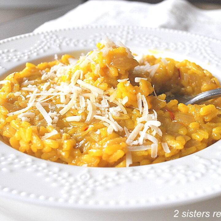 A white plate filled with yellow rice, and a forkful of rice topped with shredded cheese.