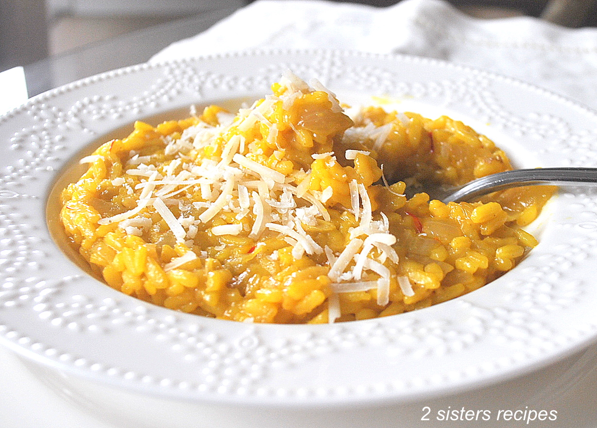 A white plate filled with yellow rice, and a forkful of rice topped with shredded cheese.