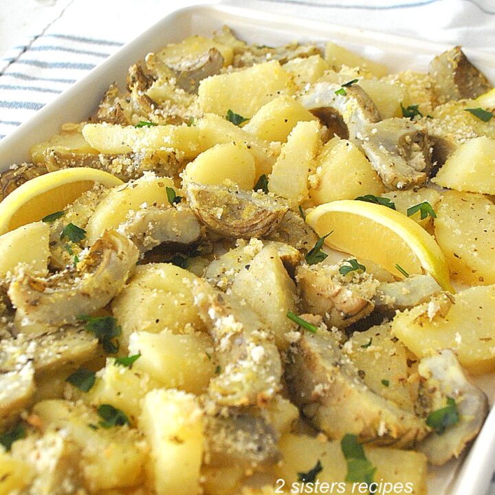 A sheet pan filled with roasted sliced potatoes and sliced artichoke bottoms.