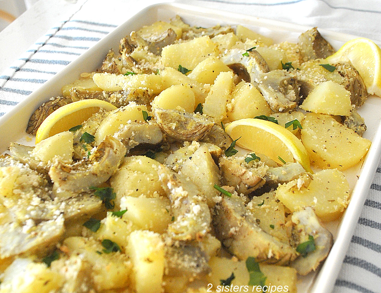 A sheet pan filled with roasted sliced potatoes and sliced artichoke bottoms.