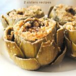 Three stuffed artichokes set on a white plate.