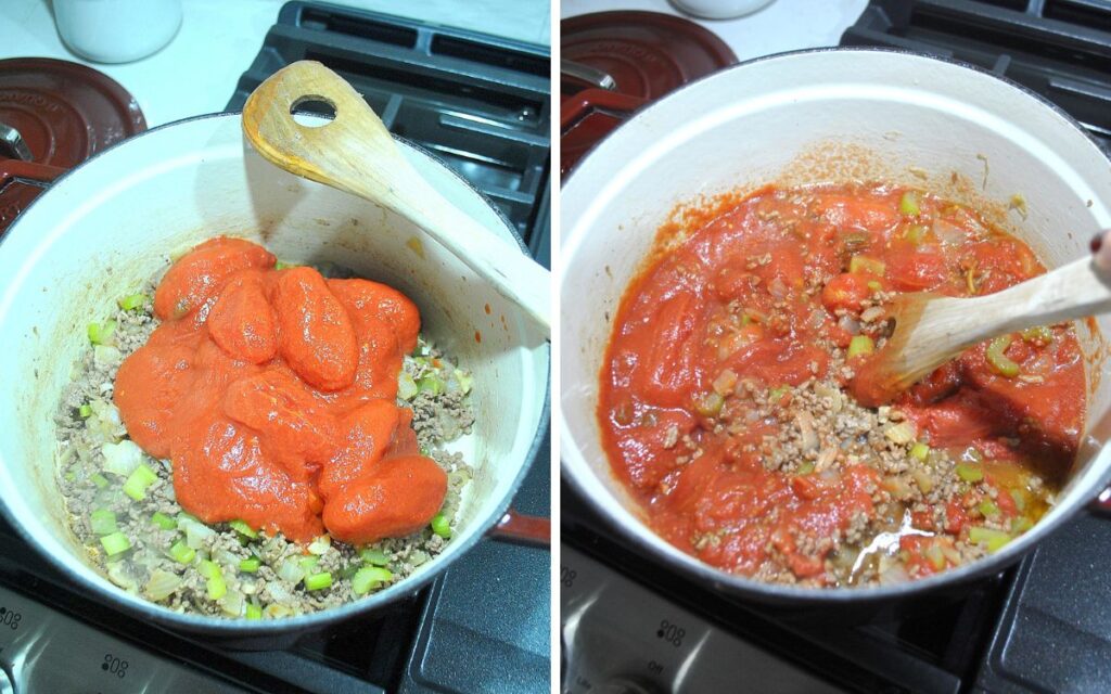 A Dutch oven filled with brown ground beef topped with peel tomatoes, and wooden spoon breaking them up.