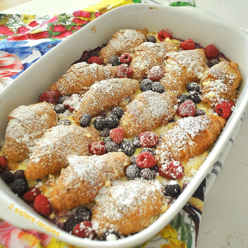 A baking dish filled with croissants, baked with custard and berries casserole.
