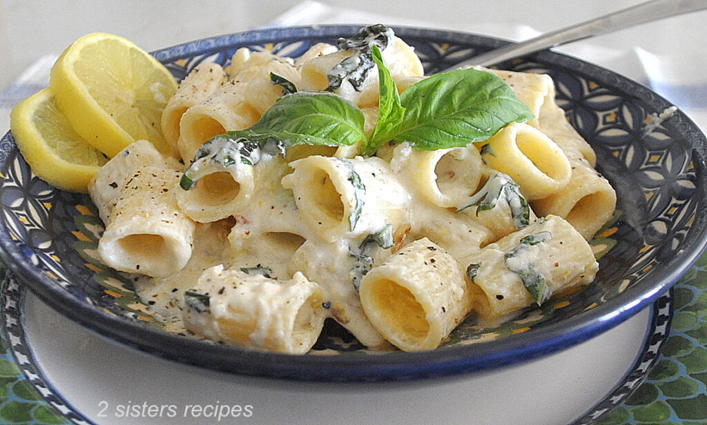 A blue bowl filled with short rigatoni with a creamy ricotta sauce.