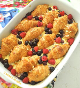 A casserole with baked croissants, custard and berries.