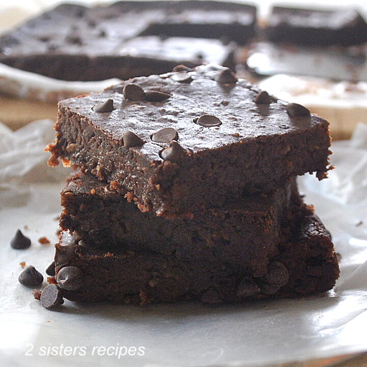 A pile of flourless fudgy brownies piled on top of one another.