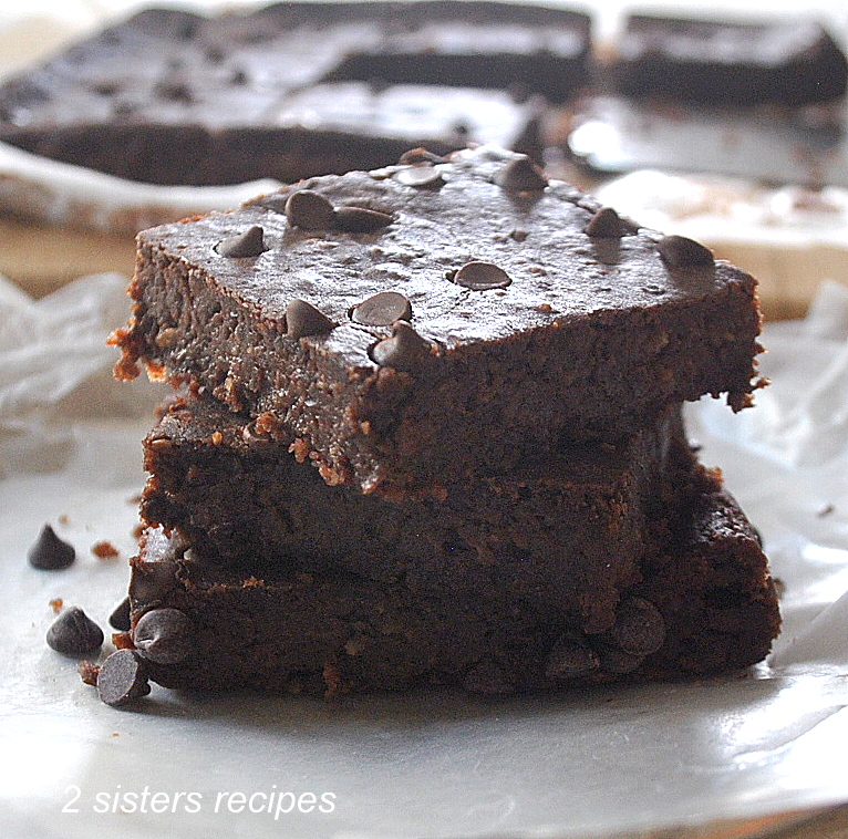 A pile of flourless fudgy brownies piled on top of one another.