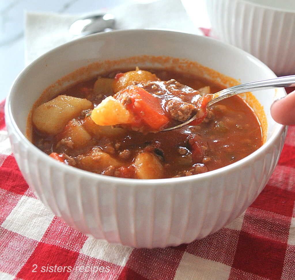 A spoonful of hearty hamburger soup, with veggies.