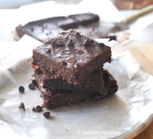 Three flourless brownies are piled on a plate.