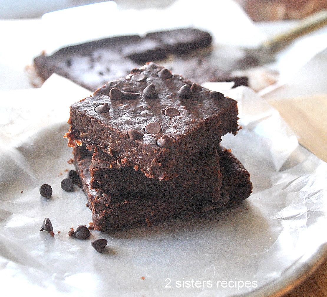 Three flourless brownies are piled on a plate.