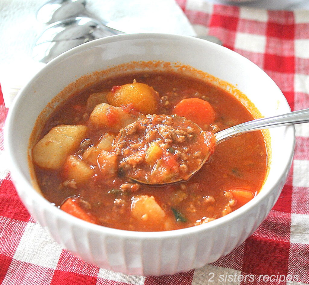 A spoonful of hamburger soup in a tomato broth.