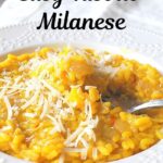 A forkful of gold-hue color risotto served in a white plate.